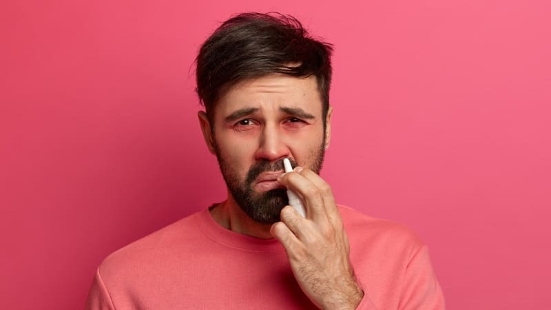 رجل يستخدم منديلًا بسبب سيلان الأنف الناتج عن اللحمية