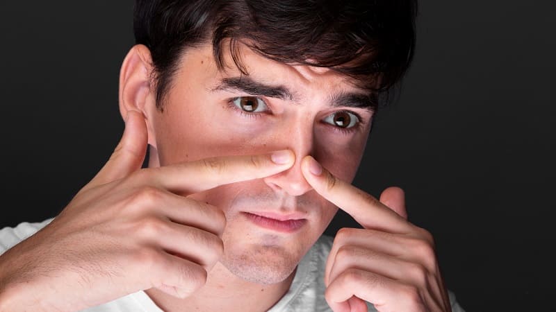 رجل يفحص أنفه لمعرفة سبب الألم أو التضخم الناتج عن التهاب لحمية الانف.